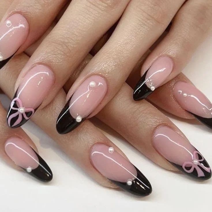 Uñas acrílicas rosas con francesa negra, lazos y detalles perlados